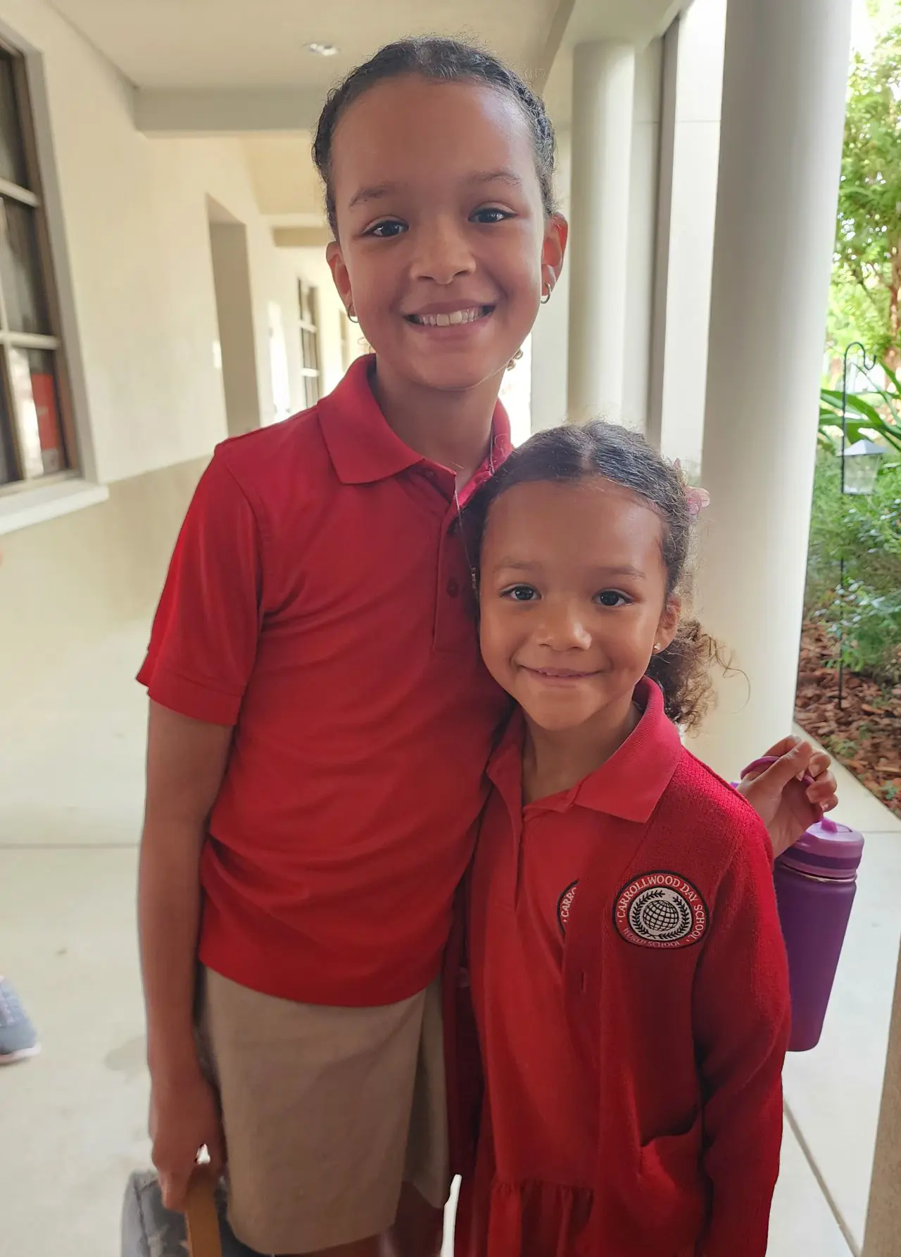 Two siblings standing and smiling and hugging each other