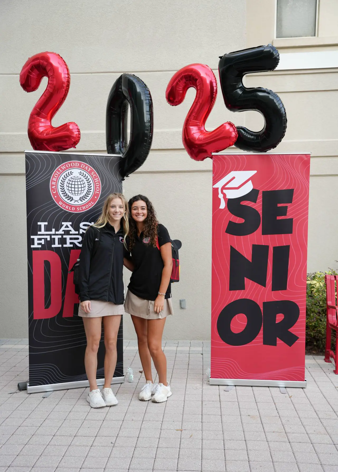 Two senior students in front of 2025 balloons