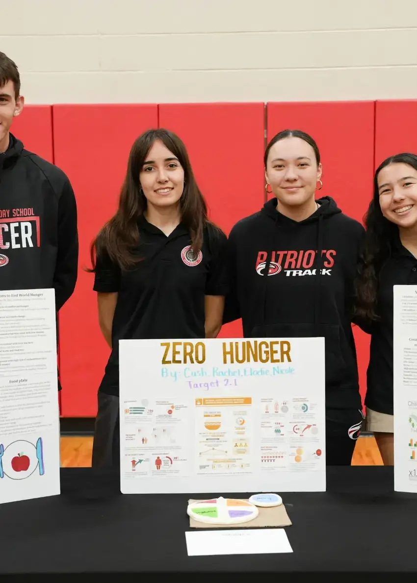 Four students behind their board to end hunger